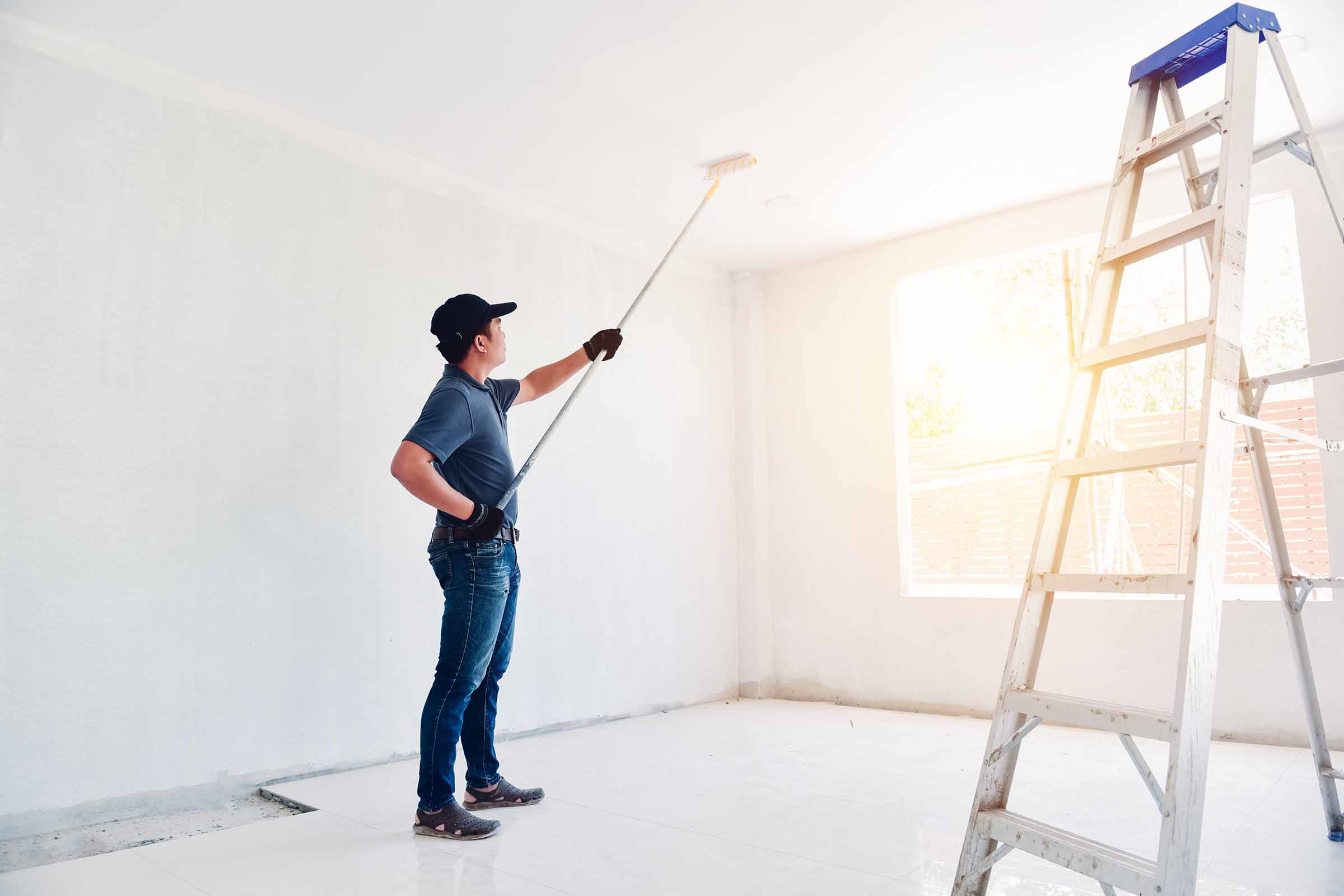 Asian Rear View Of A Male Painter Drawing A Wall With Paint Roll