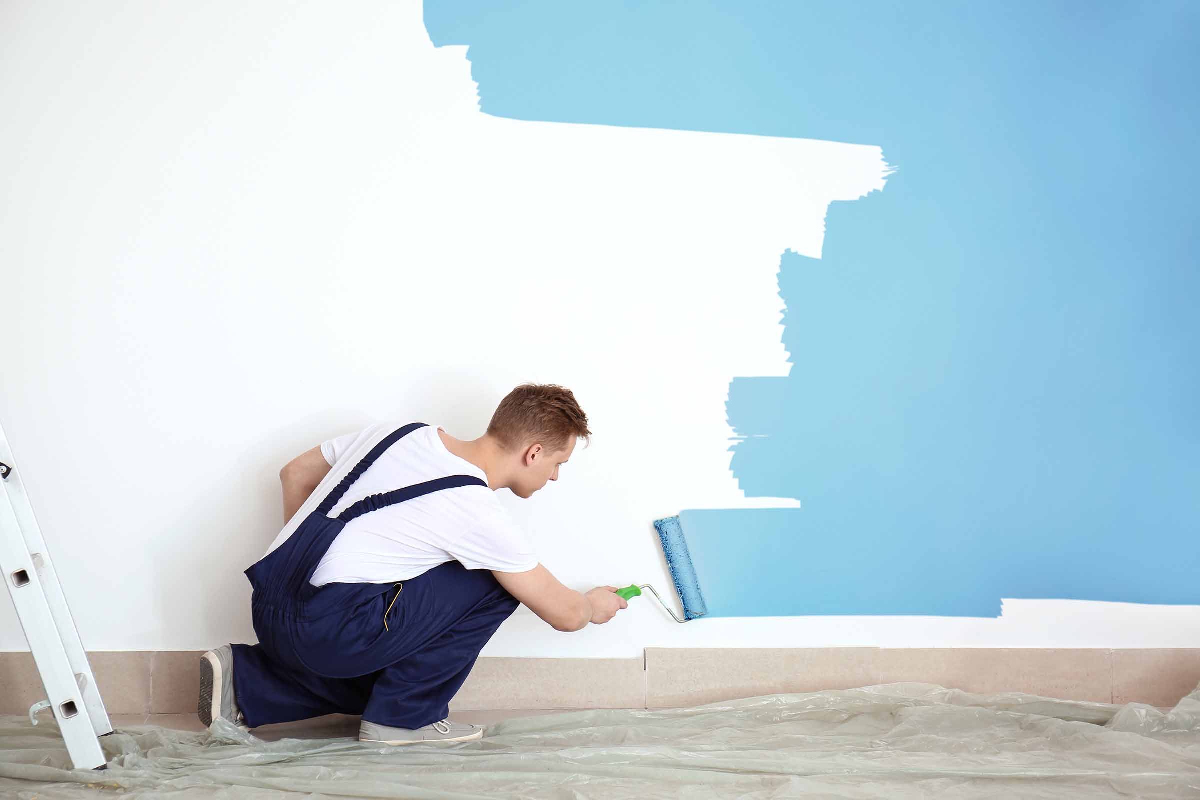 Male Painter Using Roller For Refurbishing Color Of Wall Indoors